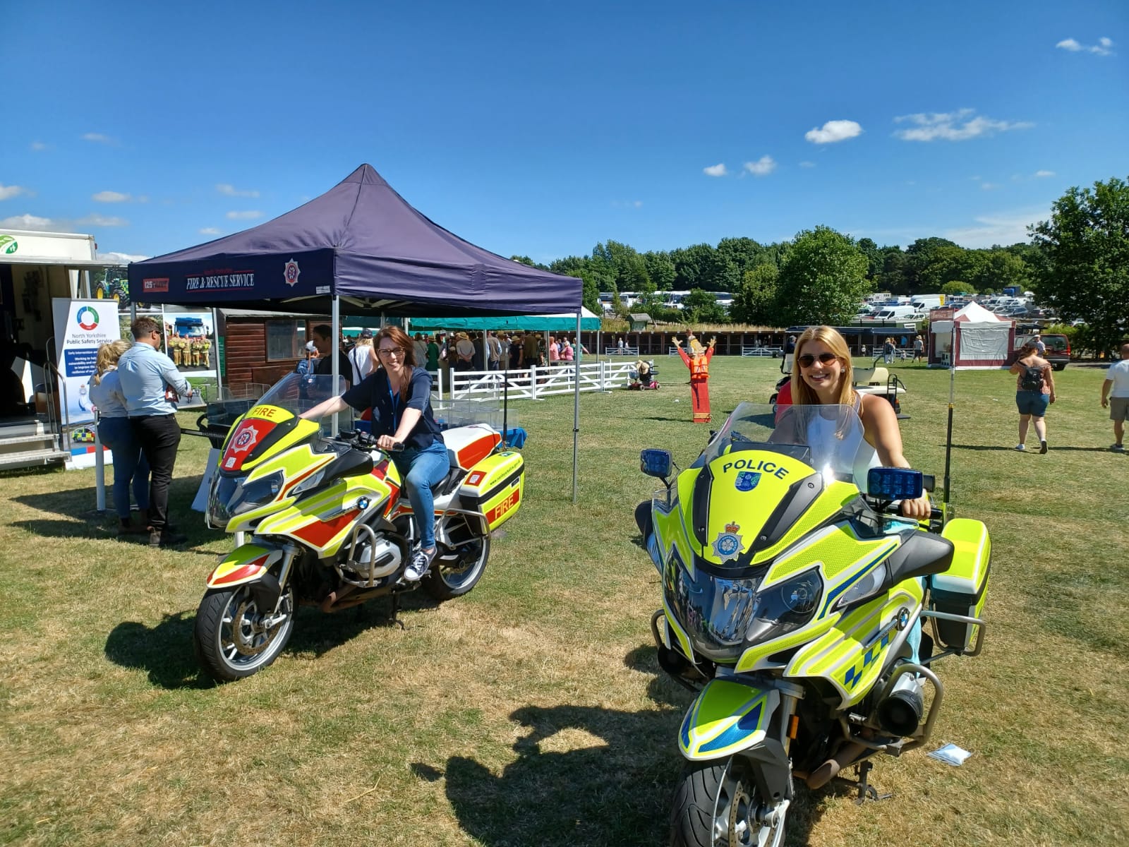 Police and fire motorbikes being sat on by two women at the Great Yorkshire Show