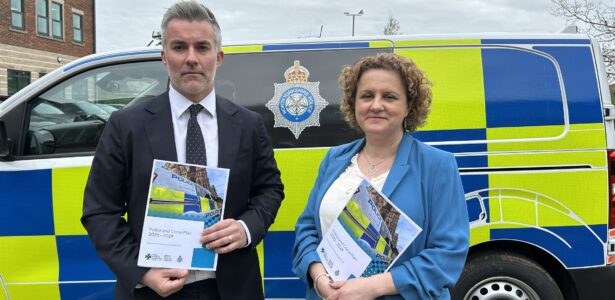 David Skaith and Jo Coles stand in front of police vehicle holding the Police and Crime plan